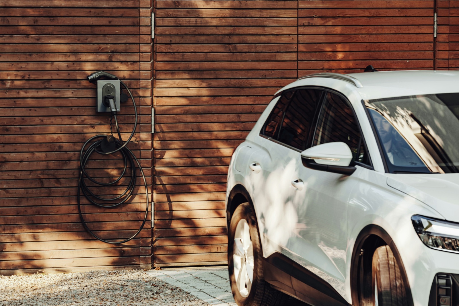 Voiture en charge devant une maison équipée d’une borne murale, illustration